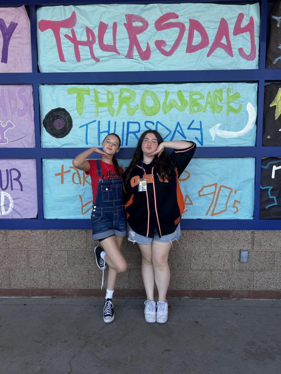 Madalyn Reiter (11) and Nora Baltera (10) pose in front of Student Councils spirit day windows in their 90's gear on Throwback Thursday.