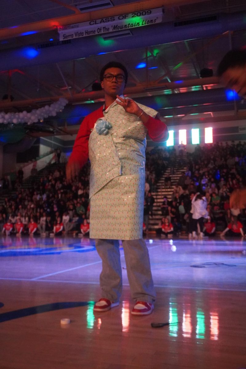 Festive Frenzy. Senior Class President Nehemiah Brown (12) competing in the present wrapping challenge during the Winter Assembly.