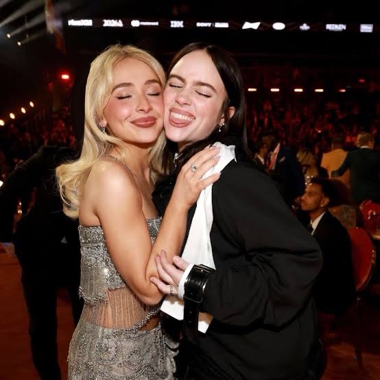 Sabrina Carpenter and Billie Eilish share a candid moment on the floor during the Grammy's ceremony, drawing attention with their playful pose and red carpet glamour. Uploaded a work by Chris Pizzello liscensed under cc-by-4.0 https://commons.wikimedia.org/wiki/File:Sabrina_Carpenter_and_Billie_Eilish_at_the_Grammys.jpg
