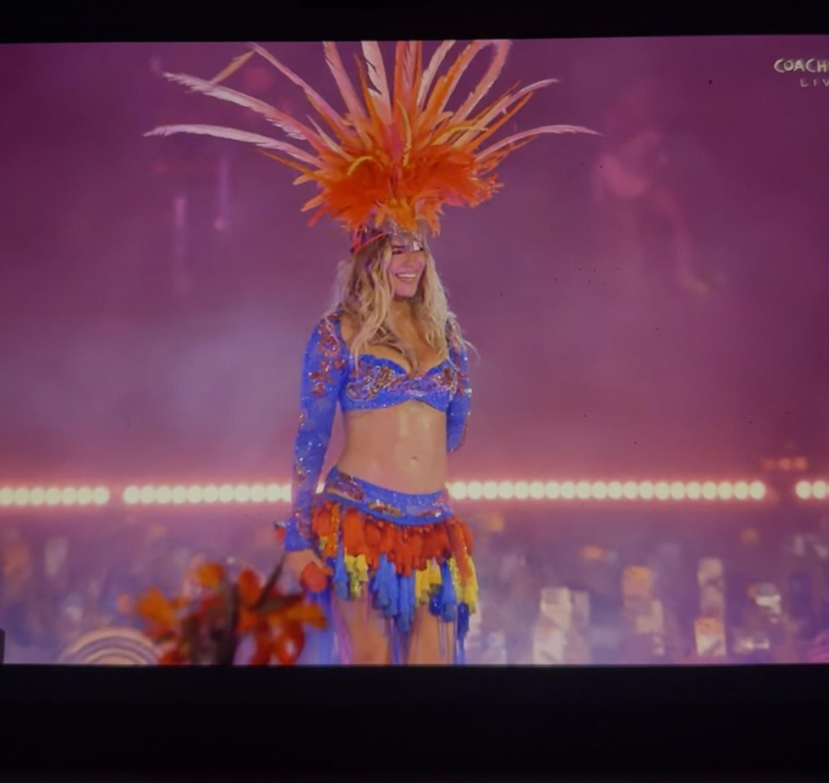 Karol G performs during her historic headlining set at Coachella, wearing a vibrant outfit inspired by Latin American culture and celebration. Her performance highlighted the way music and cultural expression unites audiences from different backgrounds. Image captured from the official Coachella livestream.